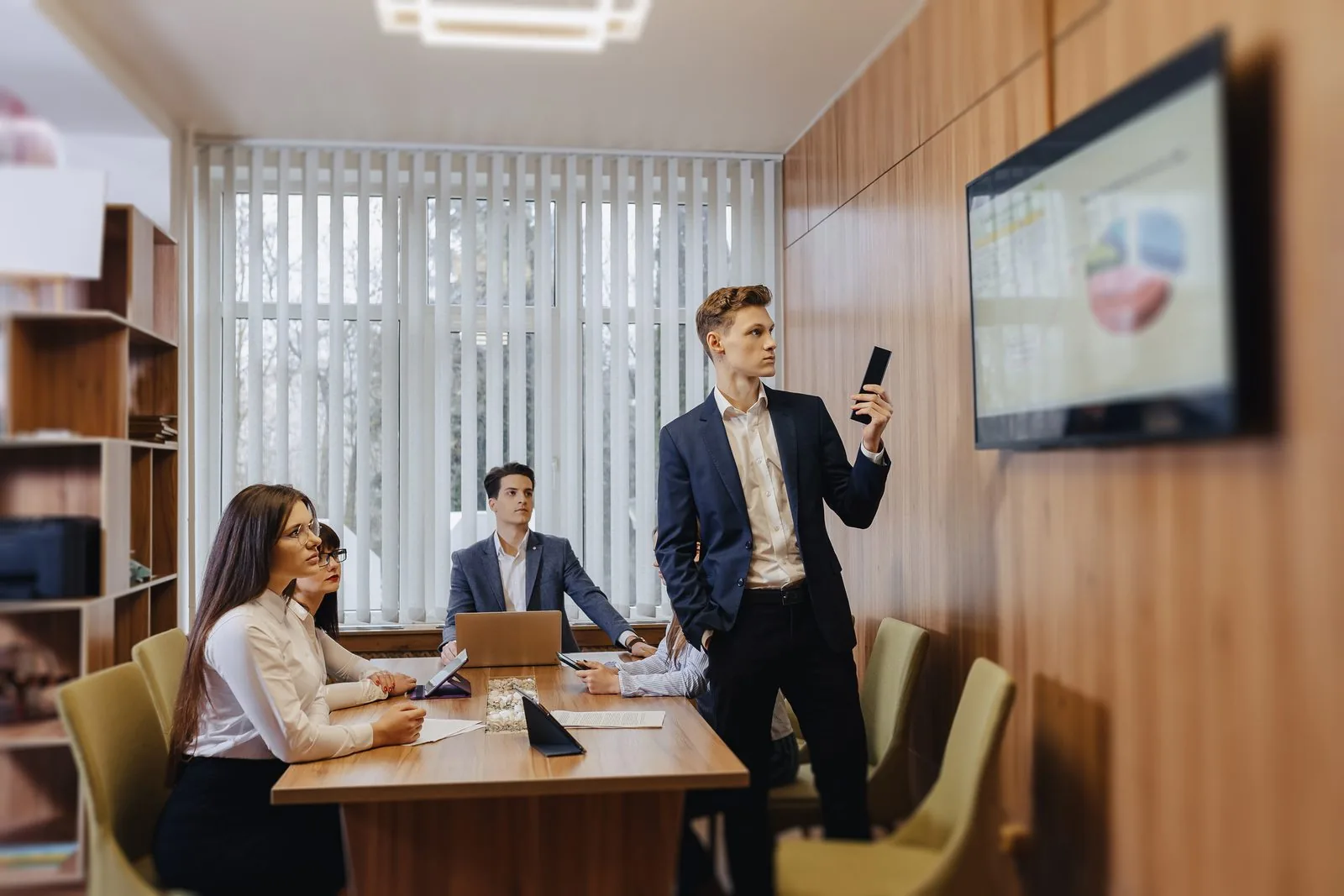 Equipe em sala de reunião acompanhando indicadores em uma tela de TV