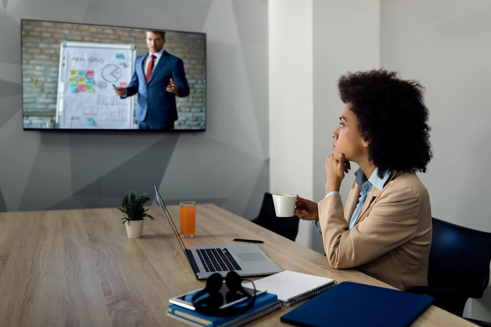 Colaboradora assistindo a um treinamento exibido em uma tela de TV